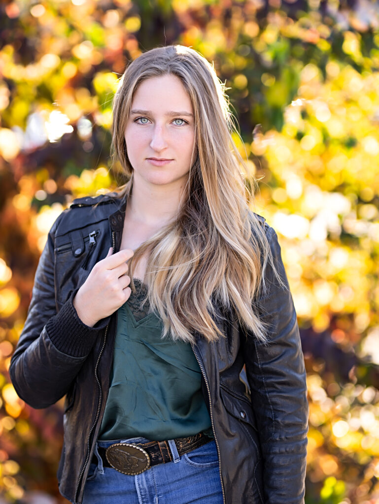 blond senior in a leather jacket with fall colors