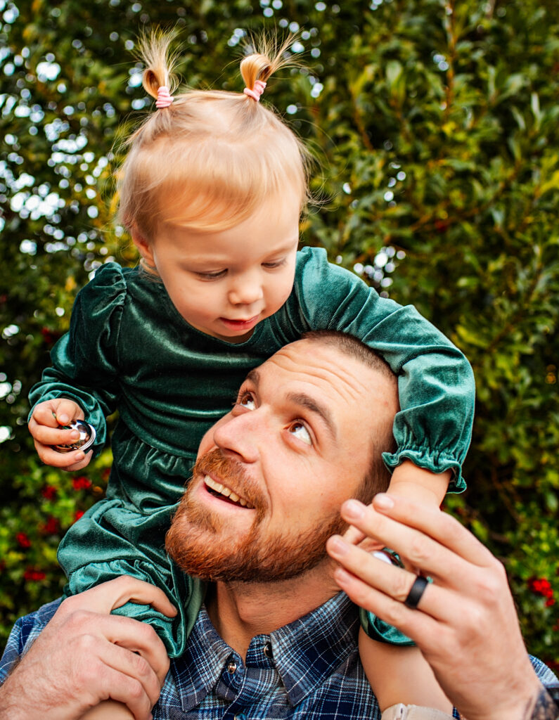 Dad holds little girl on his shoulder for family photos